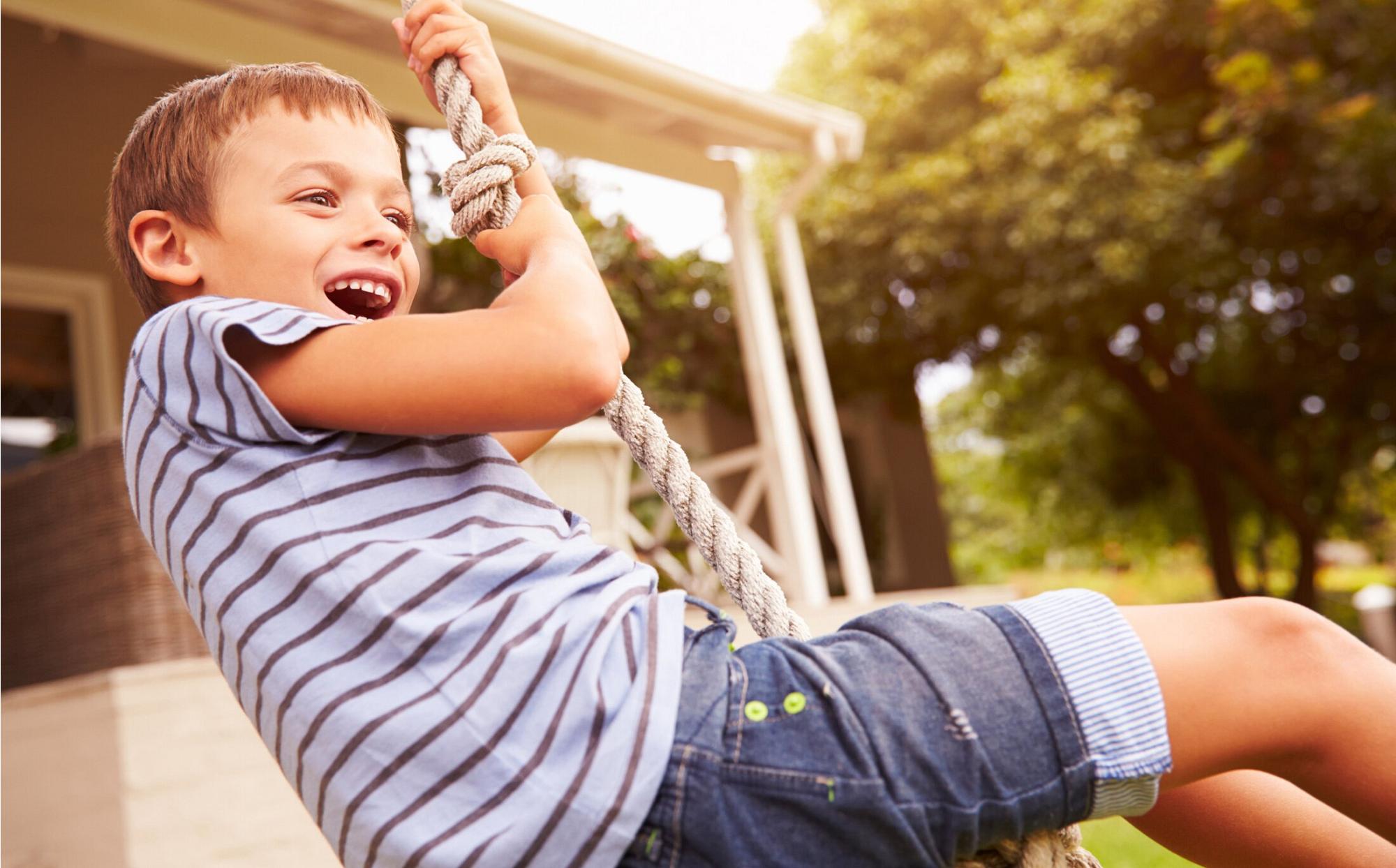 Child swinging on rope and smiling